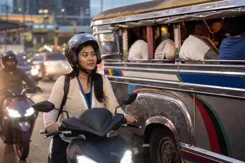 A call-center worker on her scooter next to a jeepney