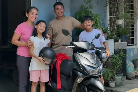 A family with their new scooter in front of their house