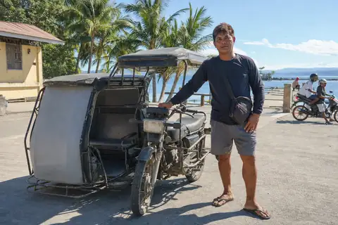 A tricycle driver beside his motorcycle with sidecar at the terminal